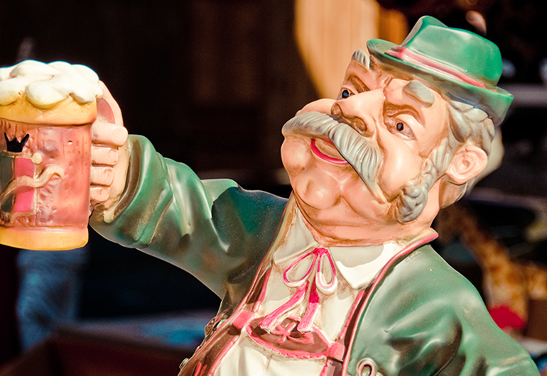 A figurine wearing Lederhosen and holding a stein.